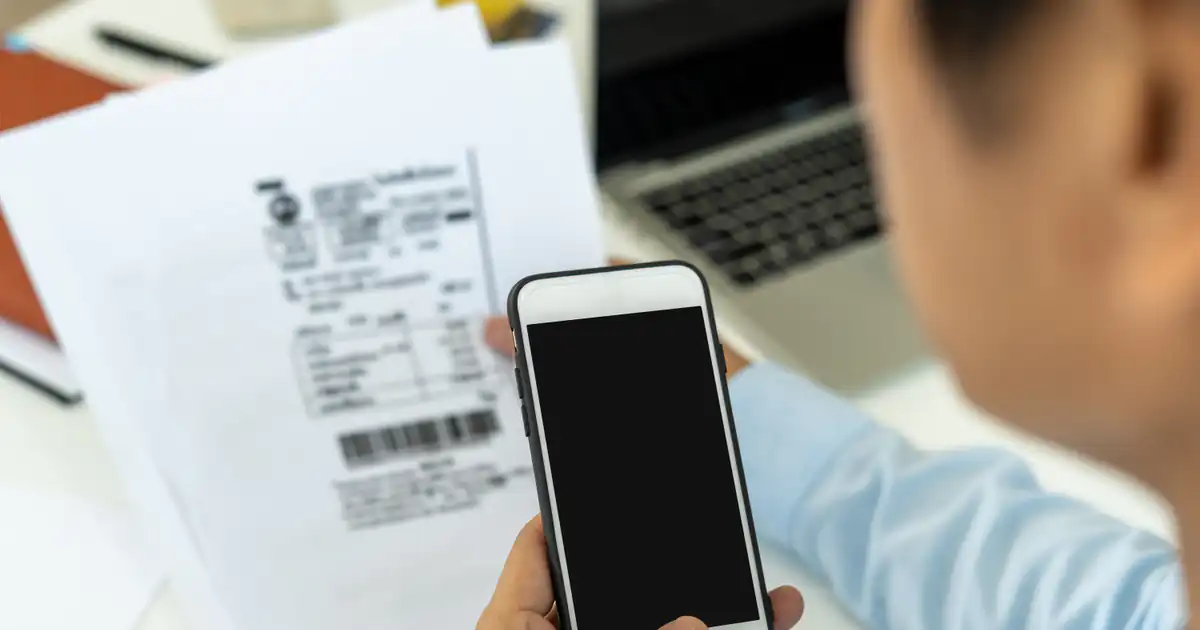 Persona fotografiando un ticket de compra con el móvil