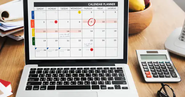 Portátil con un calendario marcado en pantalla junto a una calculadora