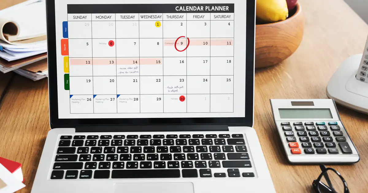 Portátil con un calendario marcado en pantalla junto a una calculadora
