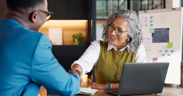 Asesora estrechando la mano de un nuevo cliente en la oficina