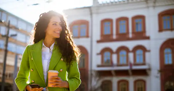 Mujer con café paseando por una calle de Lisboa