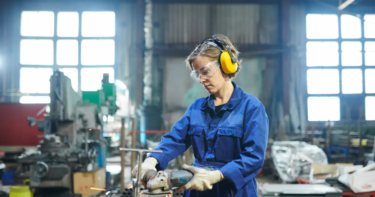 Operaria con protección auditiva trabajando en un taller industrial