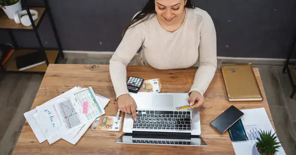 Autónoma revisando facturas y cuentas con portátil y calculadora