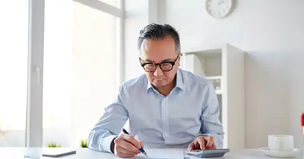 Profesional rellenando un formulario en su escritorio con calculadora