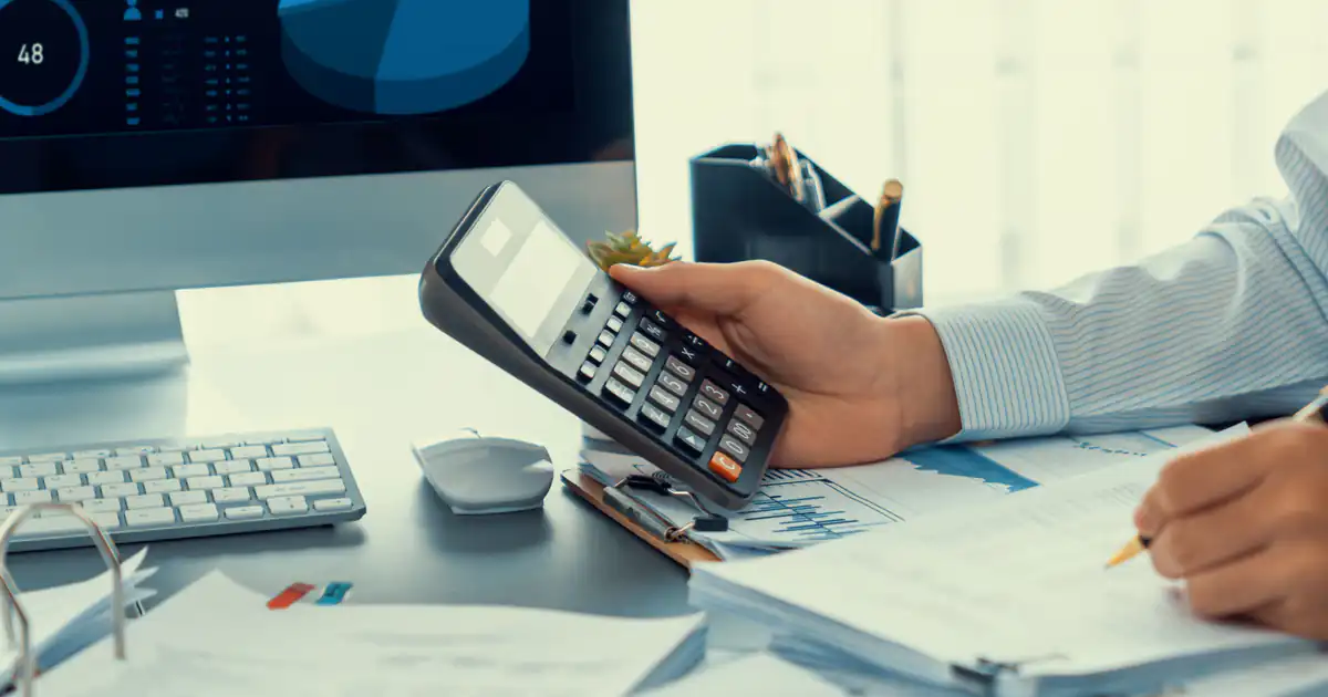 Manos calculando cuentas con calculadora y documentos contables