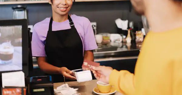 Dependienta entregando un ticket de compra en una cafetería
