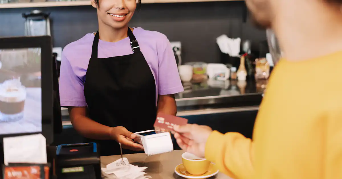 Dependienta entregando un ticket de compra en una cafetería