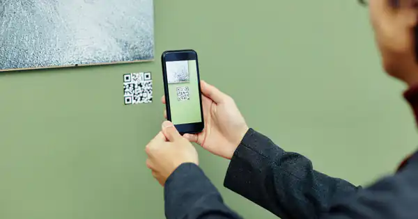Empleado escaneando con el móvil un código QR en la pared