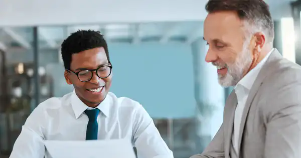 Asesor revisando documentos con un cliente sonriente en la oficina