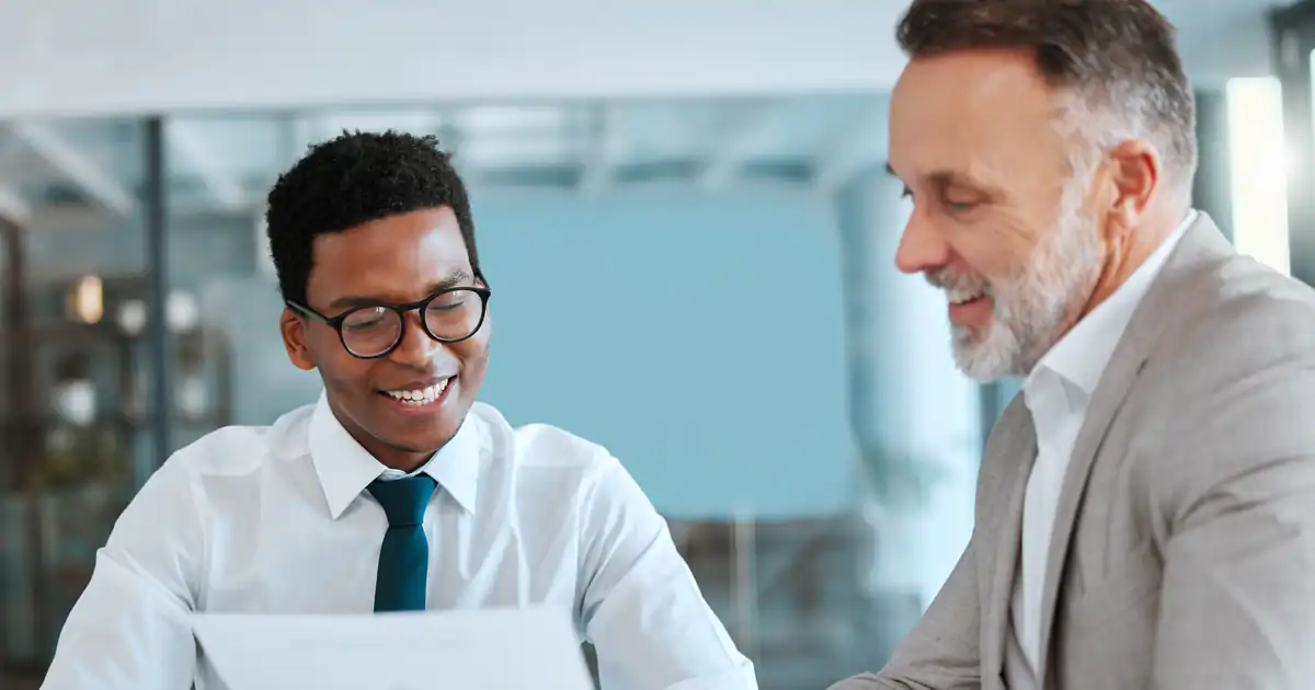 Asesor revisando documentos con un cliente sonriente en la oficina