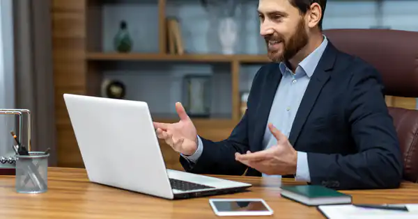 Asesor sonriente atendiendo a un cliente por videollamada desde su despacho