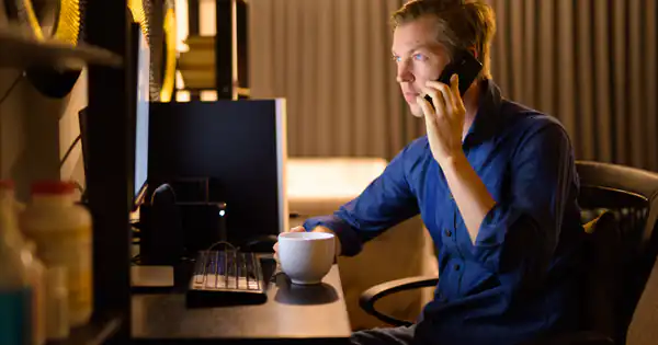 Trabajador atendiendo una llamada en su escritorio a última hora
