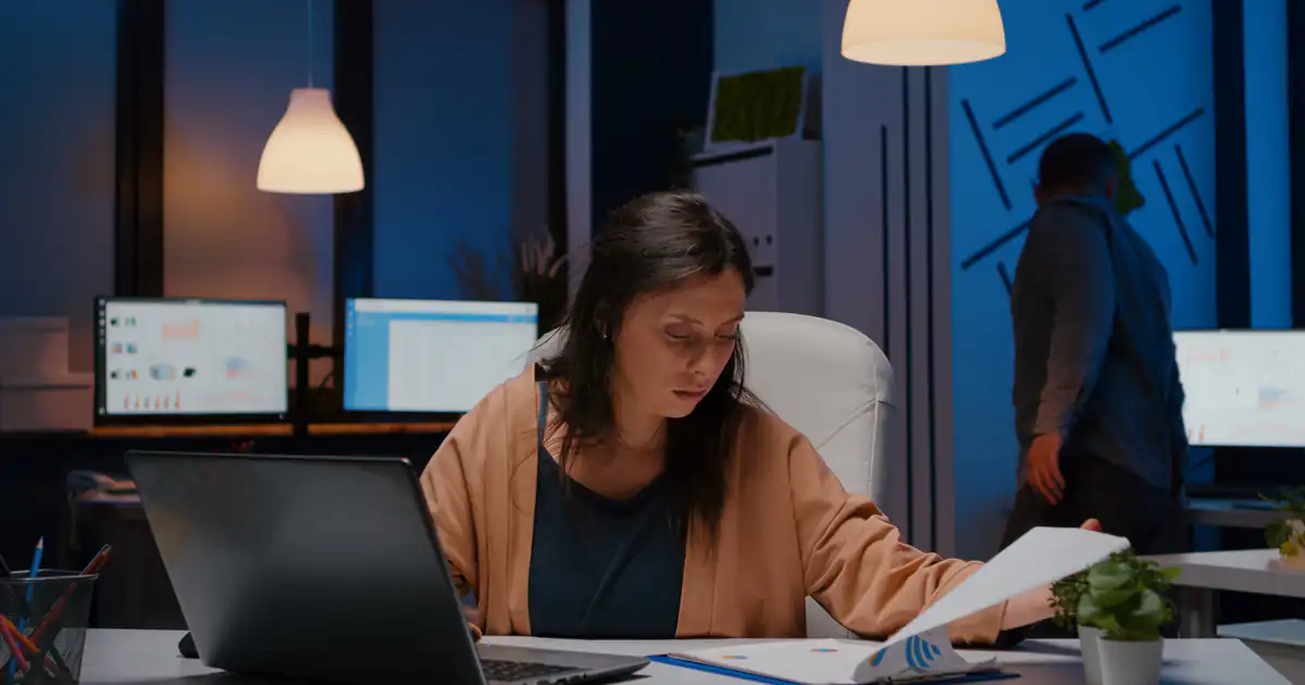 Empleada revisando documentos en la oficina al caer la tarde
