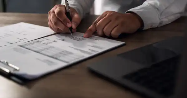 Manos revisando una factura impresa con bolígrafo sobre la mesa