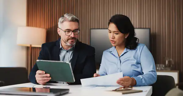 Dos profesionales revisando documentación y una tableta en el despacho