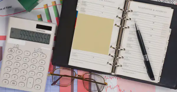Agenda abierta con calculadora y bolígrafo sobre la mesa de trabajo