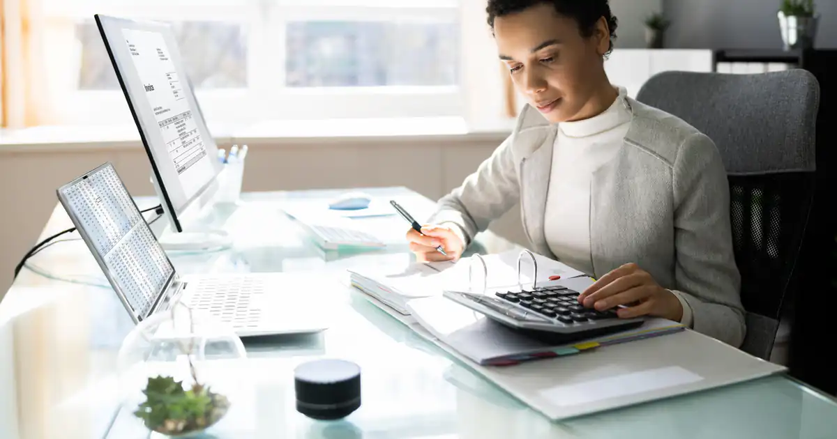 Contable trabajando con calculadora y documentos en una oficina luminosa