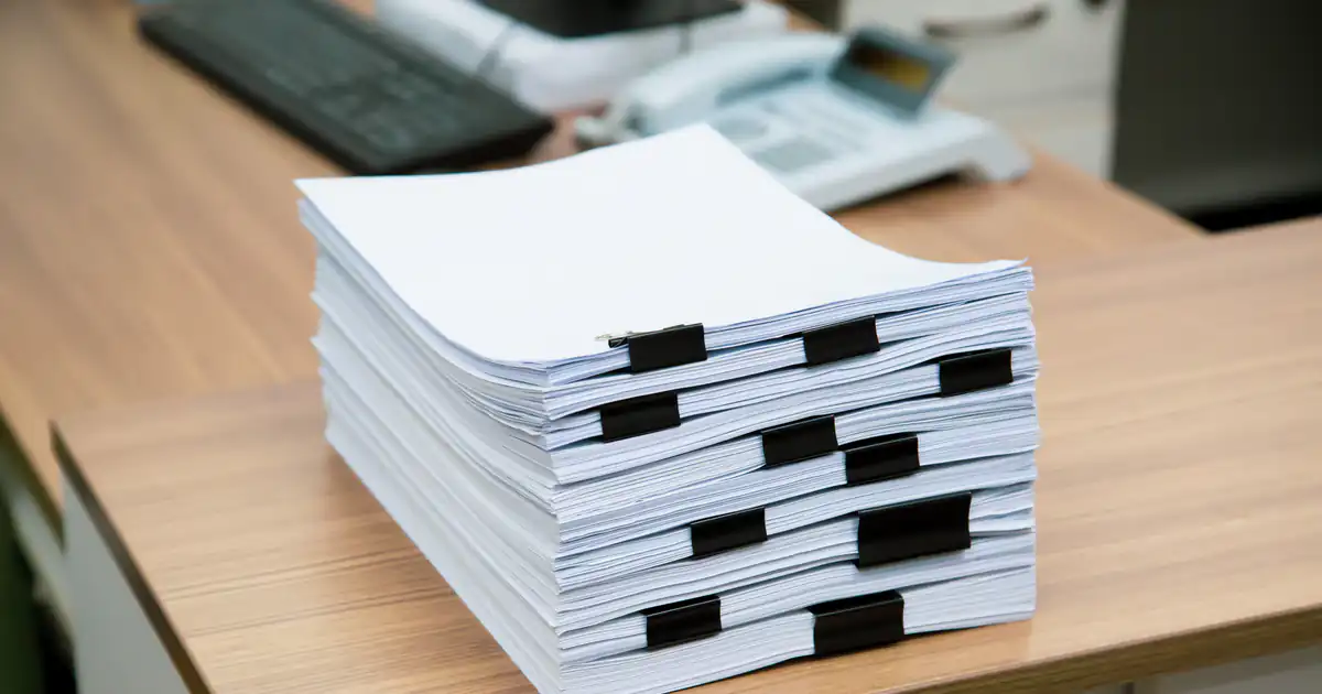 Montón de documentos sujetos con pinzas sobre una mesa