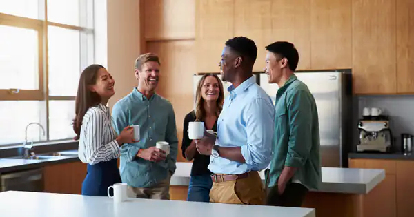 Compañeros charlando con un café en la cocina de la oficina