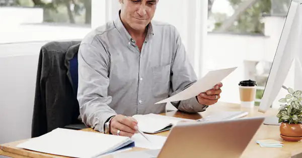 Empresario revisando documentos con tranquilidad en su despacho