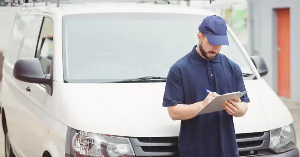 Técnico con gorra anotando en un portapapeles junto a su furgoneta