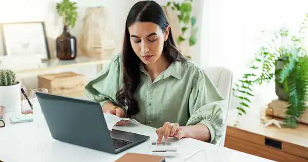 Profesional autónoma calculando retenciones con calculadora y portátil en casa