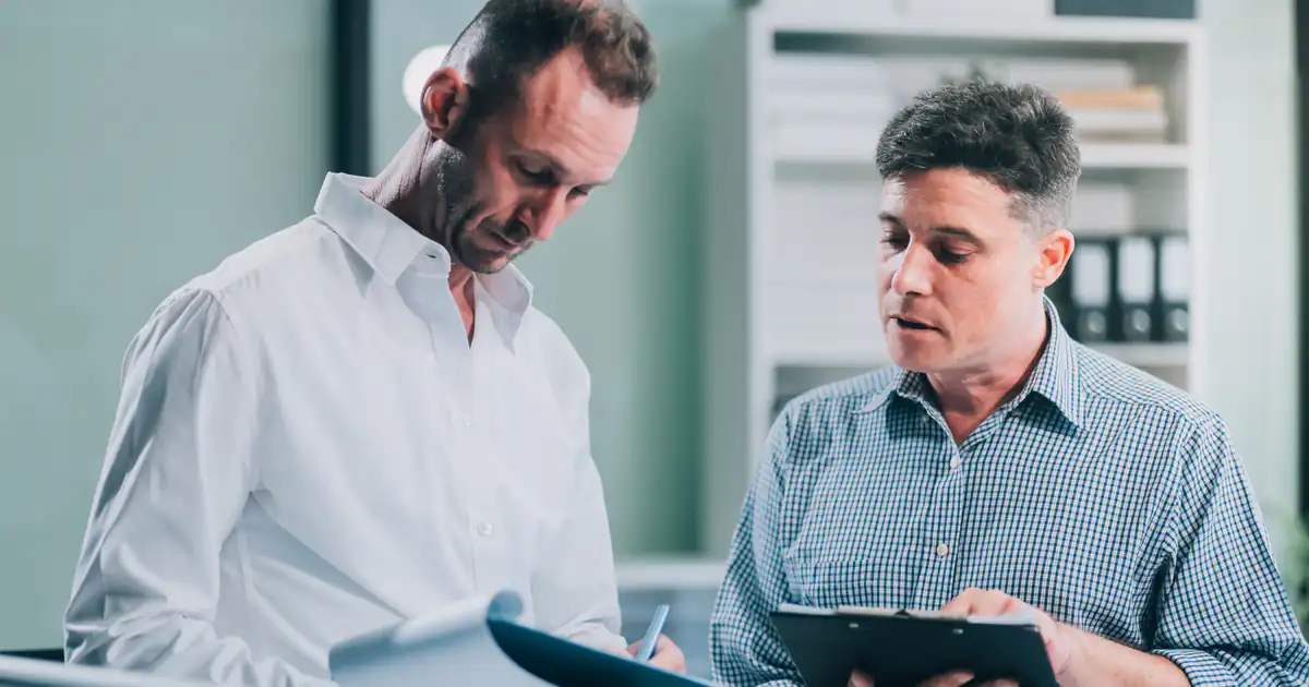 Dos hombres revisando documentación con una tableta en una oficina